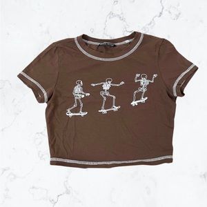 Brown cropped T shirt short sleeved with three dancing skeletons on skateboards